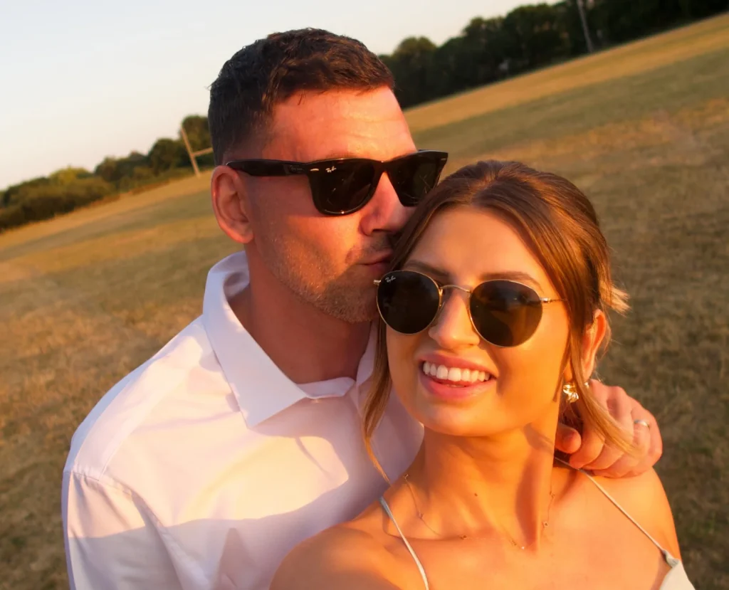 Matthew Spicer and Beth posing together in a field at golden hour