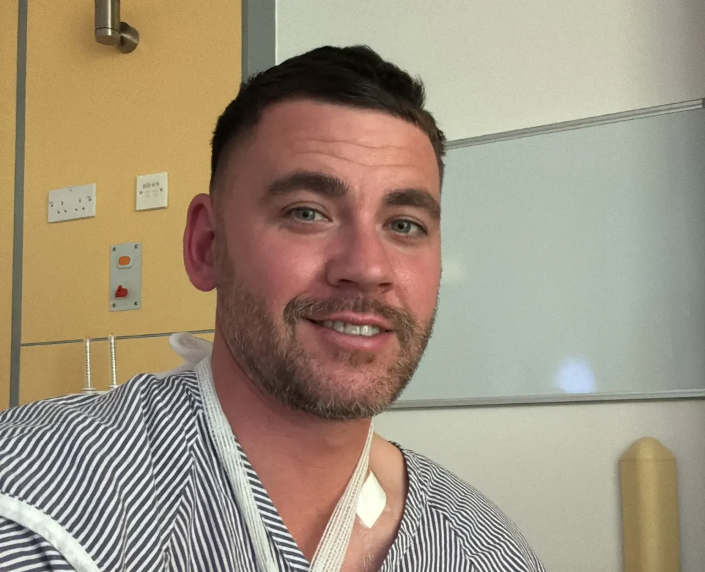 Matthew Spicer smiling at the camera in a hospital striped shirt