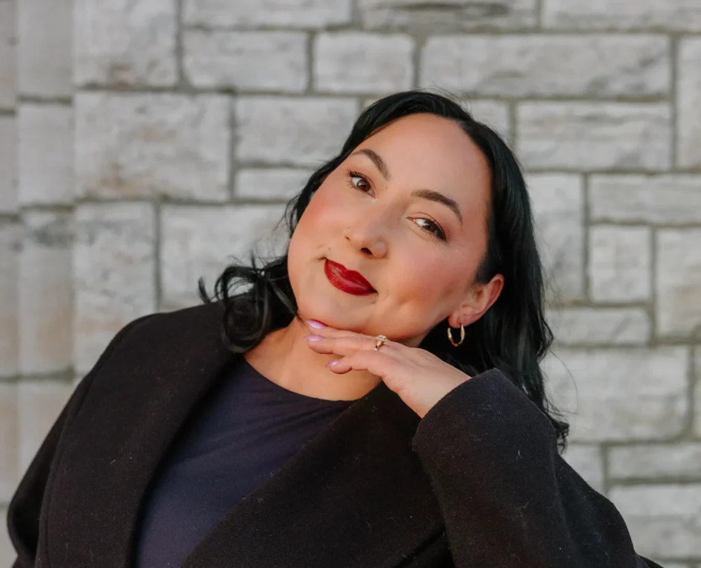 Natashia Mack posing outdoors in a black cardigan and jewellery.