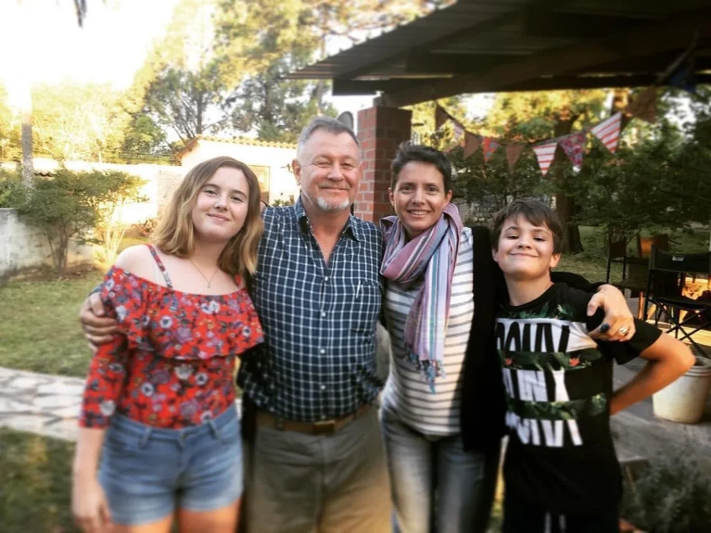A man in khaki clothing with his arm round a woman and two younger people standing together.