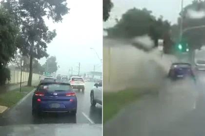Driver branded a 'scumbag' after appearing to deliberately accelerate through a massive puddle and drenching a pedestrian waiting at a bus stop during heavy rain.