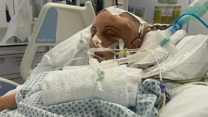 Woman in hospital bed with medical equipment wearing head covering.