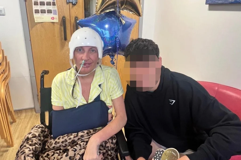 Woman in white head bandage and yellow top sitting with young man in hospital room.