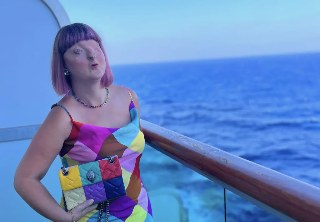 Woman in multicoloured dress on cruise ship balcony overlooking open ocean.